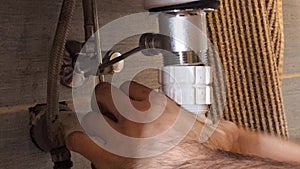 The plumber fixes the waste from the sink. A man's hands fix the plumbing under the bathroom sink. Concept of