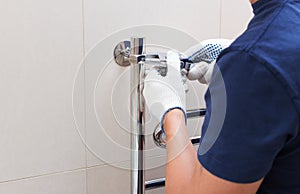 Plumber fixing chrome heated towel rail in bathroom