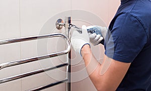 Plumber fixing chrome heated towel rail in bathroom photo