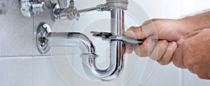 The plumber fixing a chrome pipe connection in a modern bathroom setting..AI generated image