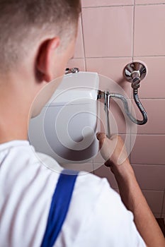 Plumber fixing a flush toilet