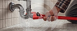 The plumber fixing a leak under the bathroom sink with a wrench..AI generated image photo