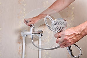 Plumber fixing leaky single handle shower faucet in bathroom.