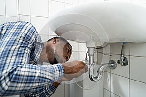 Plumber Fixing Pipe In Bathroom. Plumbing Maintenance