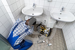Plumber Fixing Pipe In Bathroom. Plumbing Maintenance