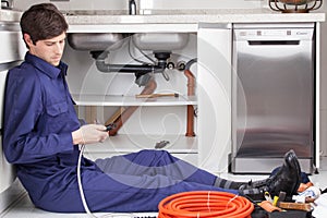 Plumber fixing the pipe sitting on the floor