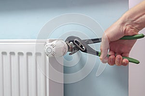 Plumber Fixing Radiator With Wrench. Heating radiator with temperature regulator, thermostat. photo