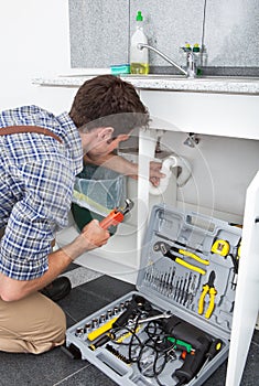 Plumber Fixing Sink In Kitchen