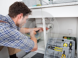 Plumber fixing sink in kitchen