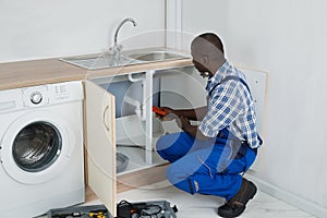 Plumber Fixing Sink In Kitchen