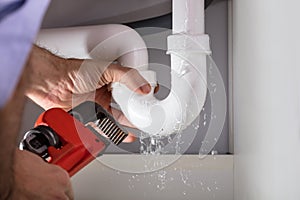 Plumber Fixing Sink Pipe With Adjustable Wrench