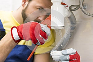 Plumber fixing the sink siphon in a bathroom photo