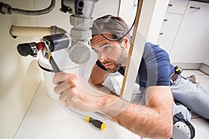 Plumber fixing under the sink