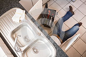 Plumber fixing under the sink