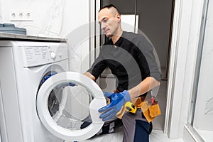 Plumber fixing washing machine on white background