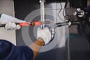 Plumber fixing white sink pipe with adjustable wrench