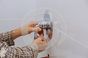 Plumber hands fixing shower mixer on modern water tap