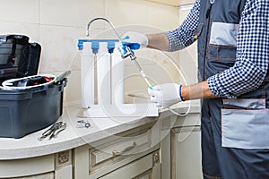 Plumber hands in gloves replace water filter cartridges at home kitchen