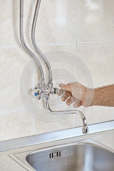 Plumber hands unscrew kitchen faucet vertical view photo
