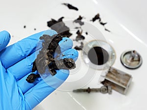 Plumber holding mass of hair and grime from clogged sink