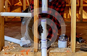 Plumber installing primer and glue PVC pipe at construction home