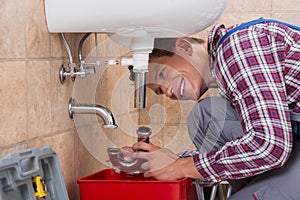 Plumber Installing Sink Pipe In Bathroom