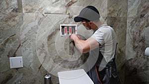 Plumber installing toilet tank in restroom