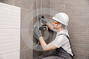 Plumber installing water taps shower stall, work in bathroom