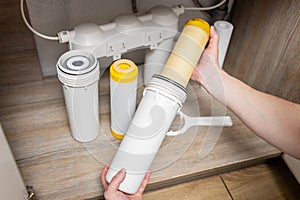 Plumber installs or change water filter. Replacement aqua filter. Repairman installing water filter cartridges in a kitchen. Clean