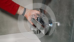 The plumber installs the shower faucet in the bathroom.