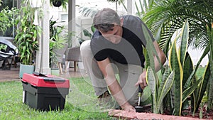 Plumber Man fixing Sprinkler Head in backyard