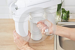 Plumber or man hand holding installation key and replace a water filter cartridges at home kitchen. Fix osmosis system