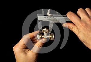 Plumber measures the size of brass fitting using a caliper before connecting water or gas pipe