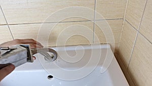 A plumber removes a faucet from a sink. Plumbing. Concept of home maintenance, minor repairs and maintenance in the