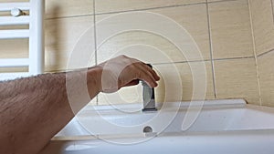 A plumber removes a tap from a bathroom sink. The plumber's hands remove the faucet from the sink. Concept of small