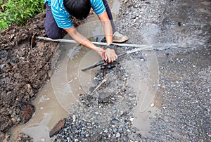 A plumber is repairing a broken pipe and replacing a hole with water on the side of the road.