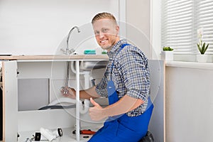 Plumber Repairing Faucet In Kitchen