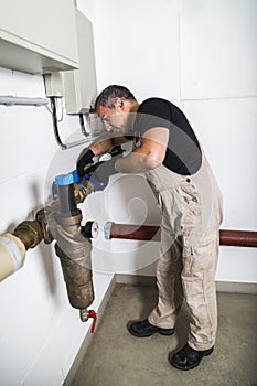 Plumber repairing metallic water pipes and looking inside