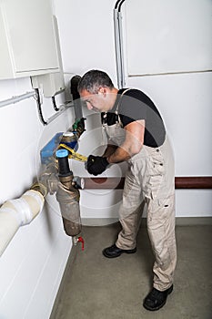 Plumber repairing metallic water pipes with wrench
