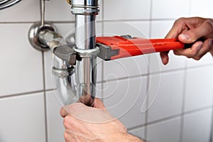 Plumber Repairing Sink With Adjustable Wrench