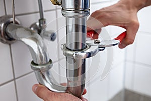 Plumber Repairing Sink With Adjustable Wrench