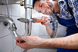 Plumber Repairing Sink In Bathroom