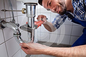 Plumber Repairing Sink In Bathroom