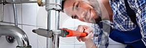 Plumber Repairing Sink In Bathroom