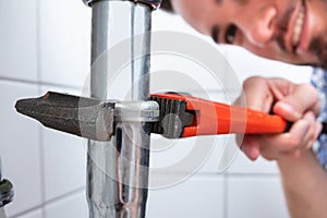 Plumber Repairing Sink In Bathroom