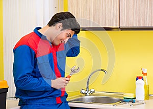 Plumber repairing tap at kitchen