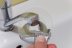 Plumber repairing a water faucet with an adjustable wrench