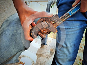 Plumber repairing water fitting with adjustable wrench