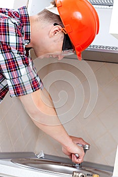 Plumber repairs kitchen faucet