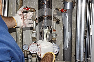 Plumber repairs pipes in plumbing unit. Hands plumbing with spanners on background of pipes, manometers and filters.